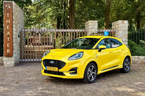 De gele Ford Puma van De Rijkoning voor een theaterhek
