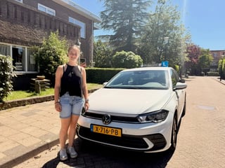 Geslaagde jonge vrouw bij een witte auto
