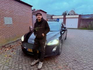 Geslaagde jongen voor de zwarte lesauto