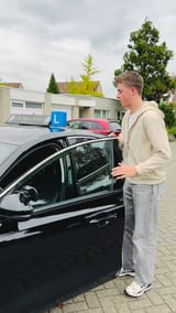 Geslaagde jongen stapt uit de lesauto