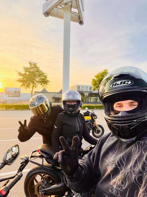 Twee motorleerlingen met helm op hun motor maken een selfie
