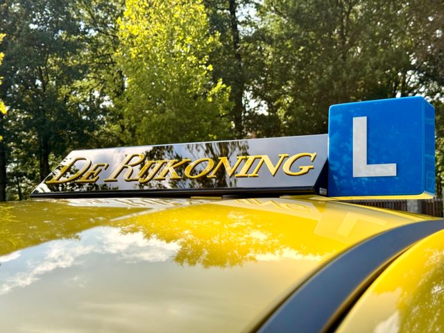 Het dakbord van De Rijkoning met gouden letters en de blauwe L op de gele Puma