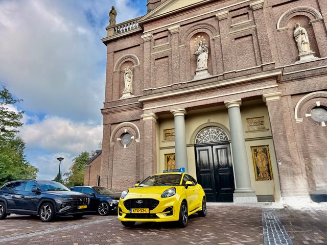 De gele Ford Puma van De Rijkoning voor een kerk