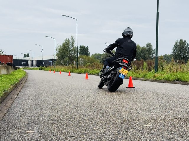 Motorleerling op het oefenterrein tussen de pionnen